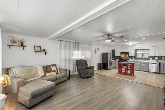 living room featuring ceiling fan, sink, and light hardwood / wood-style flooring