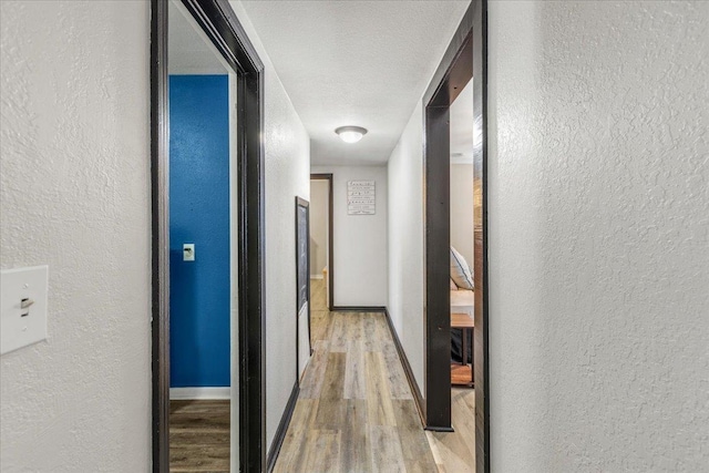 hall featuring light hardwood / wood-style floors and a textured ceiling