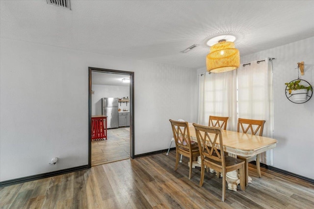 dining space with wood-type flooring and a textured ceiling