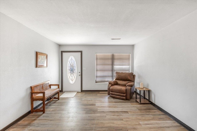 foyer entrance with a textured ceiling and light wood-type flooring