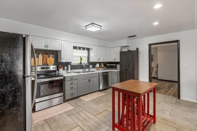 kitchen with white cabinetry, sink, gray cabinetry, and appliances with stainless steel finishes