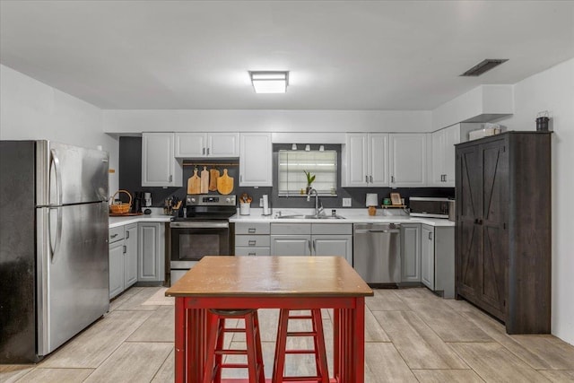 kitchen featuring gray cabinetry, sink, and appliances with stainless steel finishes