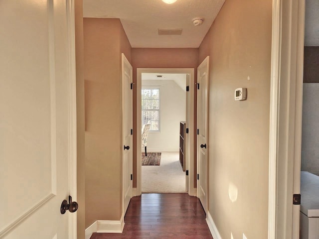 hall featuring dark wood-style flooring and baseboards