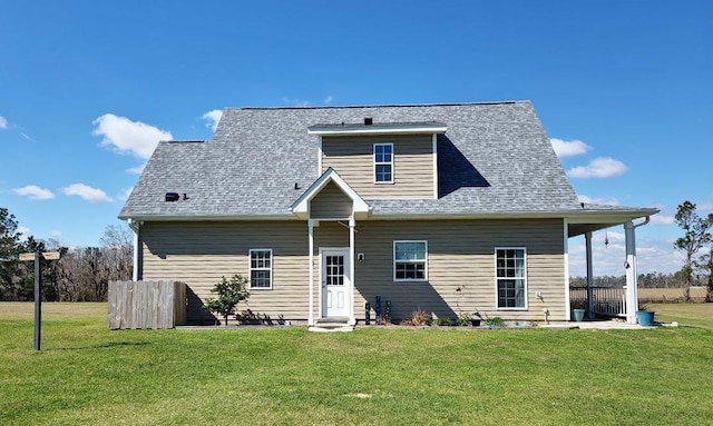 rear view of house with roof with shingles and a lawn