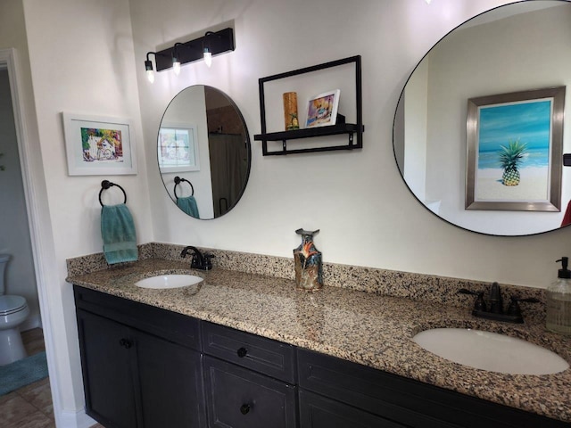 bathroom featuring double vanity, a sink, and toilet