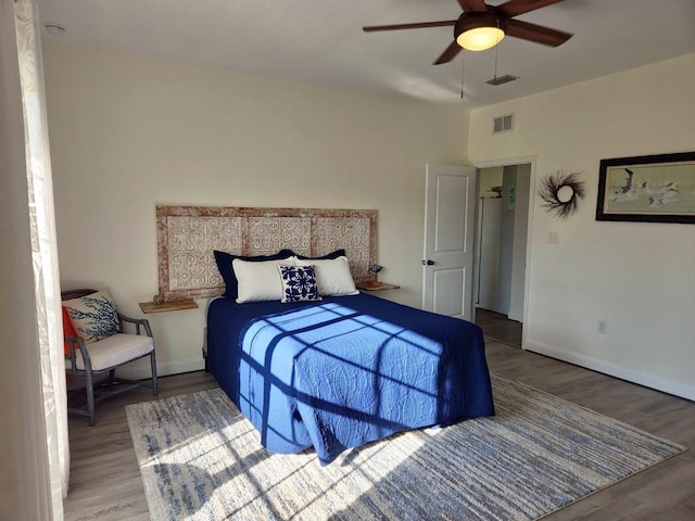 bedroom with visible vents, baseboards, and wood finished floors