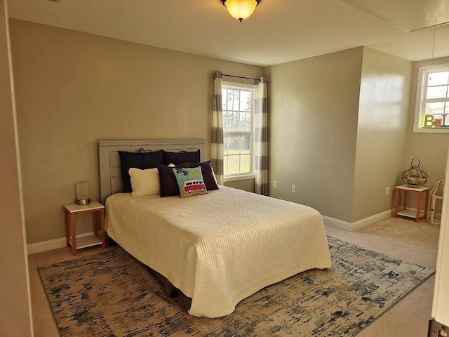 bedroom with carpet, attic access, and baseboards