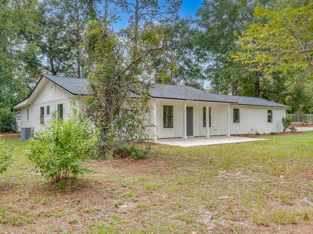 back of property with central AC unit, a patio area, and a lawn