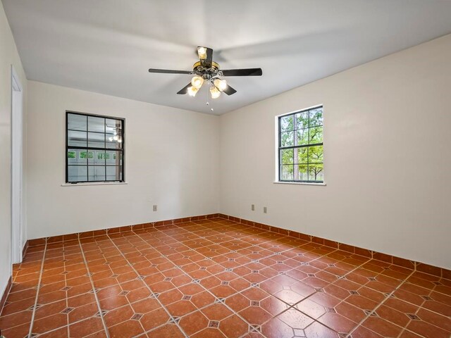 tiled empty room featuring ceiling fan