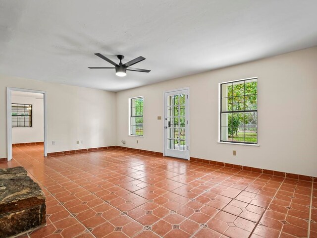 spare room with a wealth of natural light, tile patterned flooring, and ceiling fan