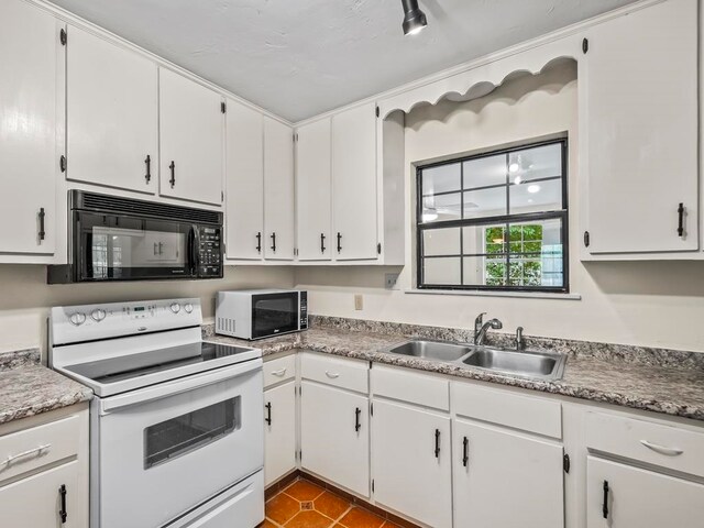 kitchen featuring white appliances, sink, tile patterned floors, and white cabinets