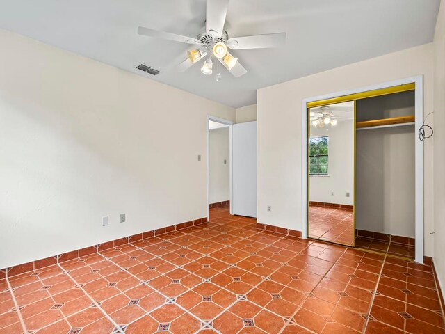 unfurnished bedroom with ceiling fan and a closet