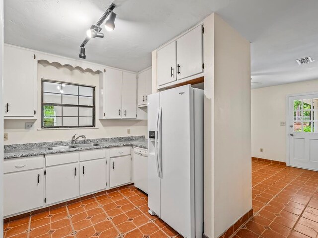 kitchen with white cabinetry, track lighting, light tile patterned floors, sink, and white appliances