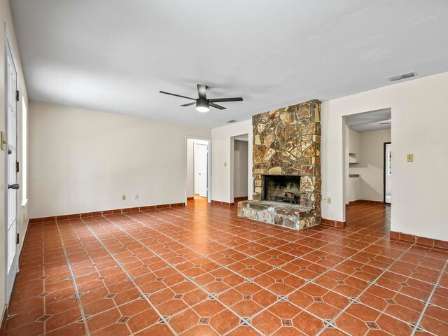 unfurnished living room featuring a fireplace, tile patterned flooring, and ceiling fan