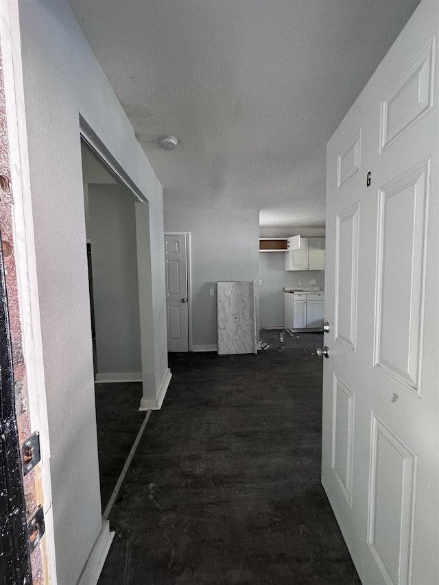 hall featuring a textured ceiling and dark wood-type flooring