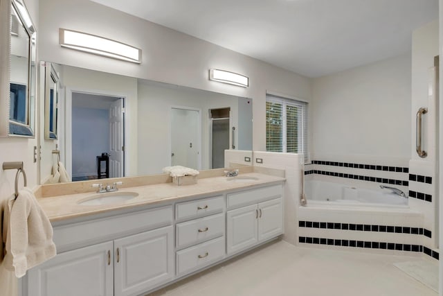 bathroom with tile patterned floors, tiled bath, and vanity