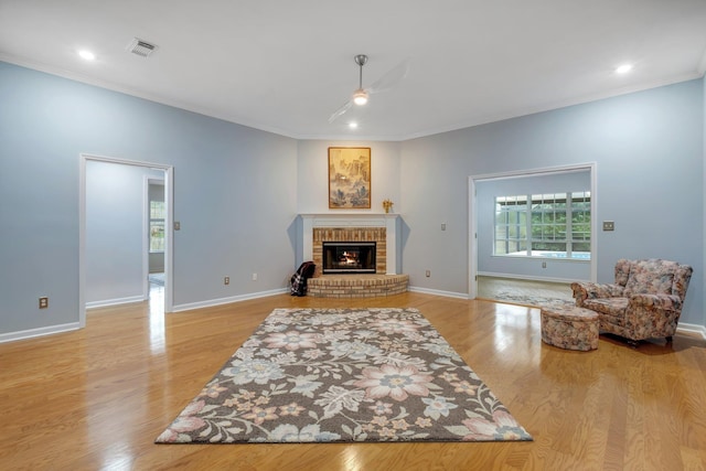 living room with a fireplace, ornamental molding, and light hardwood / wood-style floors