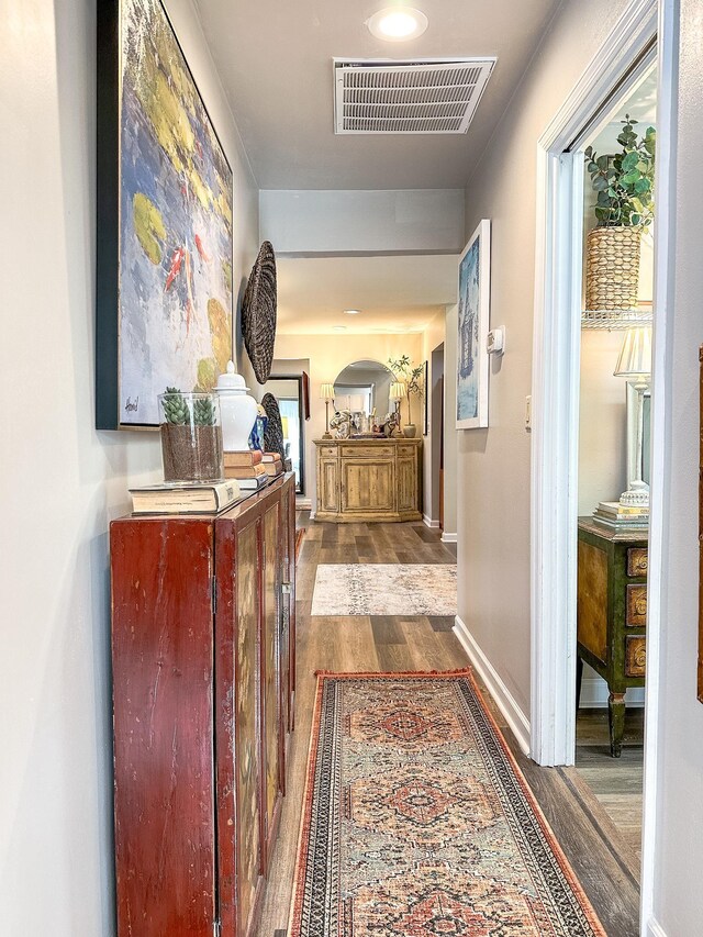 corridor featuring wood finished floors, visible vents, and baseboards