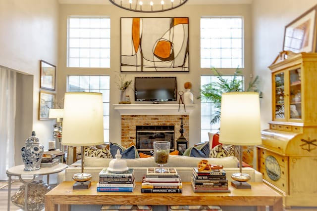 living area with a brick fireplace and a high ceiling