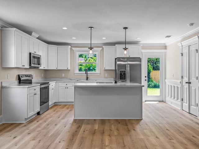 42 Duane Dr, Crawfordville, FL 32327 - kitchen featuring appliances with stainless steel finishes, light countertops, light wood finished floors, a center island, and hanging light fixtures