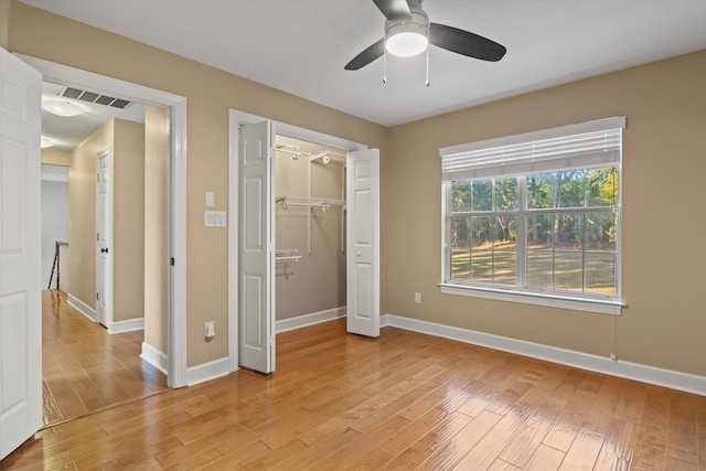 unfurnished bedroom with ceiling fan, light wood-type flooring, and a closet