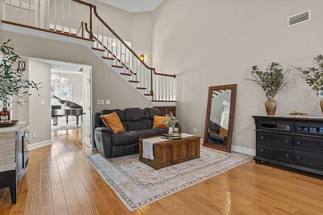 living room featuring an inviting chandelier, a towering ceiling, and hardwood / wood-style floors