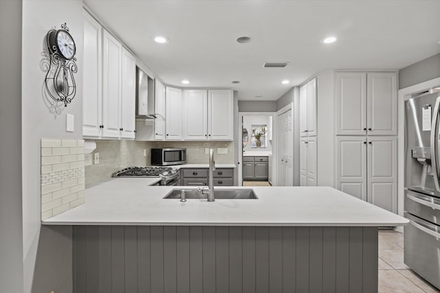 kitchen with light tile patterned flooring, sink, white cabinetry, appliances with stainless steel finishes, and kitchen peninsula