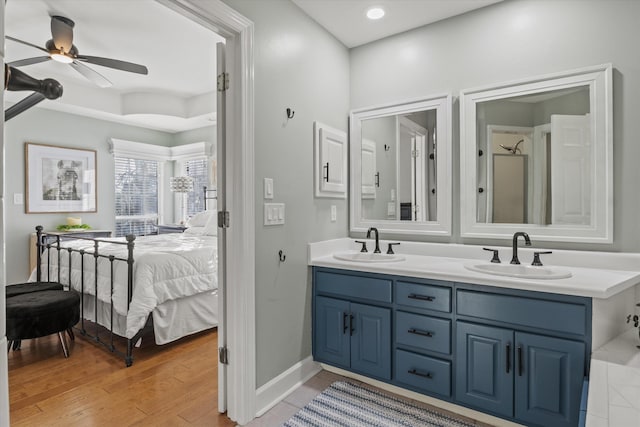 bathroom featuring hardwood / wood-style flooring, vanity, a raised ceiling, and ceiling fan