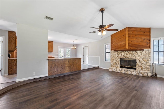 unfurnished living room featuring ceiling fan, french doors, vaulted ceiling, a stone fireplace, and dark hardwood / wood-style flooring