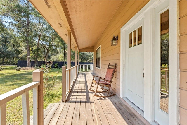 wooden deck featuring a lawn and covered porch