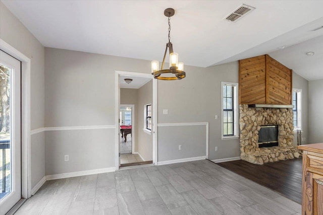 unfurnished living room featuring light hardwood / wood-style floors, a stone fireplace, a healthy amount of sunlight, and lofted ceiling