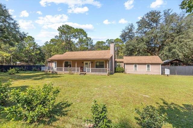 rear view of property featuring a yard and covered porch