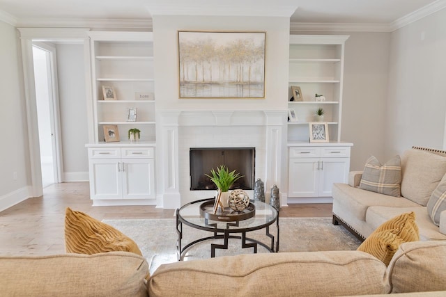 living room with a fireplace, built in features, light wood-type flooring, and ornamental molding