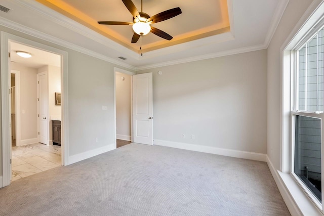 carpeted spare room with ceiling fan, crown molding, and a tray ceiling