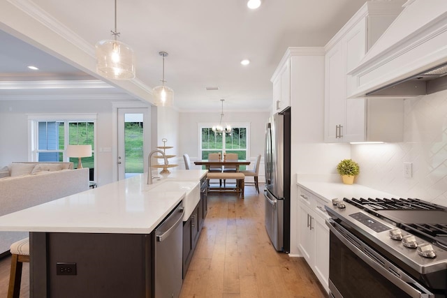 kitchen featuring stainless steel appliances, light wood-type flooring, hanging light fixtures, white cabinets, and premium range hood