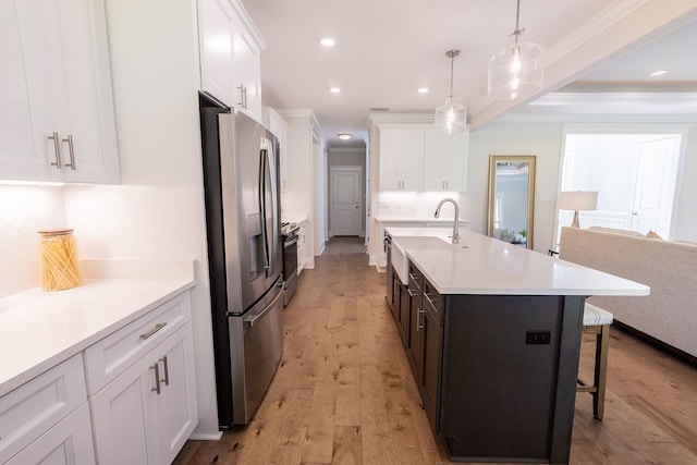 kitchen with white cabinetry, a center island with sink, light hardwood / wood-style flooring, and appliances with stainless steel finishes