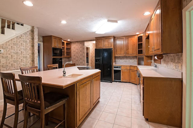 kitchen with black appliances, a breakfast bar area, sink, and an island with sink