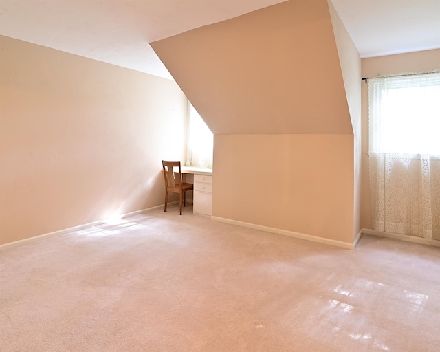 bonus room featuring vaulted ceiling, built in desk, and carpet floors