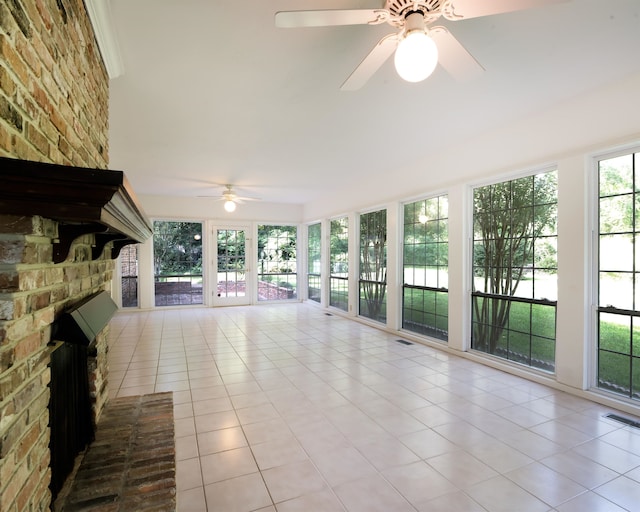 unfurnished sunroom featuring a brick fireplace and ceiling fan