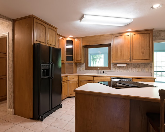 kitchen with kitchen peninsula, black refrigerator with ice dispenser, sink, and light tile patterned floors