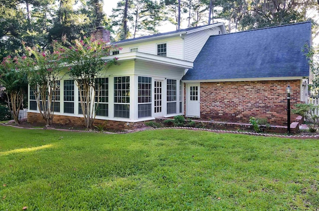 back of property with a lawn and a sunroom