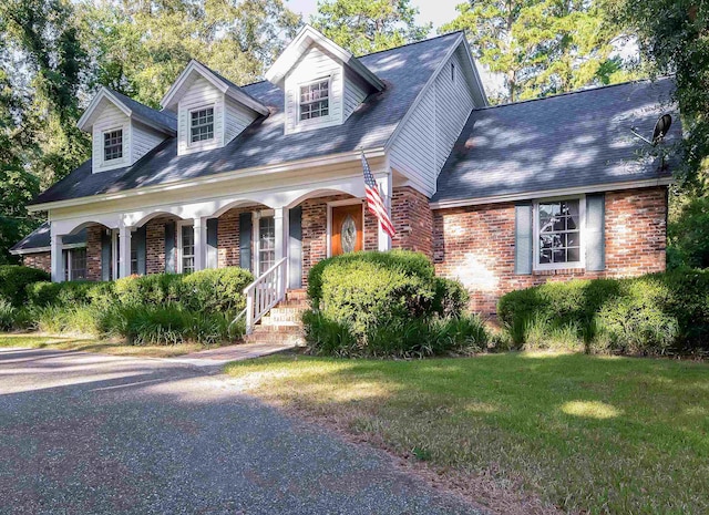 new england style home with covered porch and a front lawn