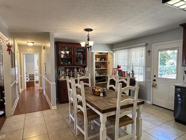 dining space featuring a chandelier, a textured ceiling, light tile patterned flooring, and baseboards