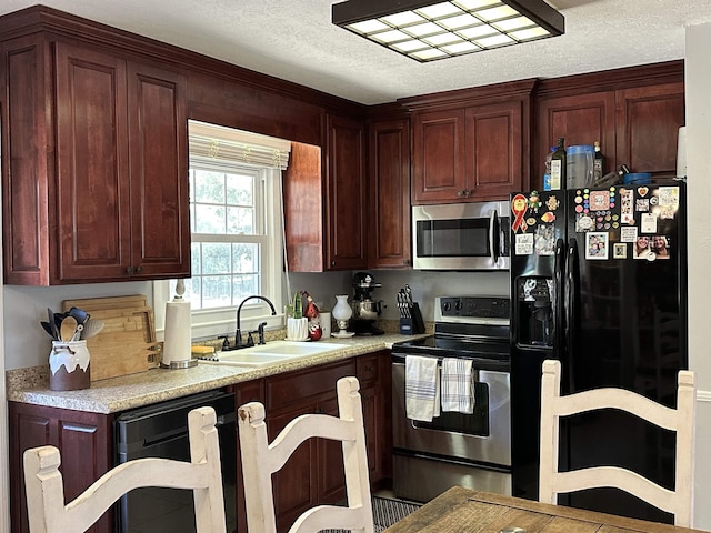 kitchen featuring a textured ceiling, black appliances, a sink, and light countertops