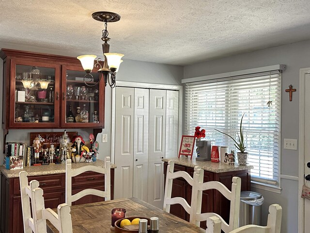 dining area with an inviting chandelier and a textured ceiling