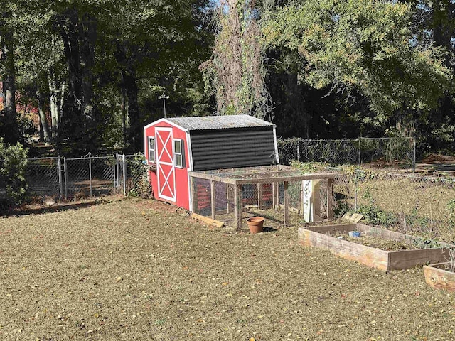 view of outdoor structure with an outbuilding, fence, and a vegetable garden