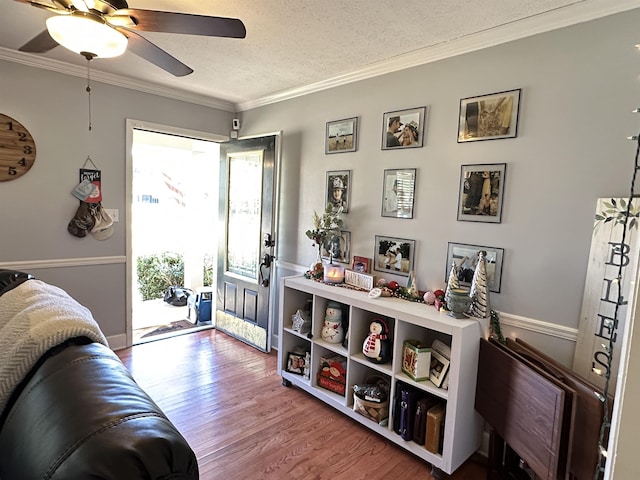 interior space with ceiling fan, crown molding, a textured ceiling, and wood finished floors