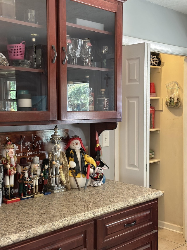 bar with a bar, light tile patterned floors, and baseboards