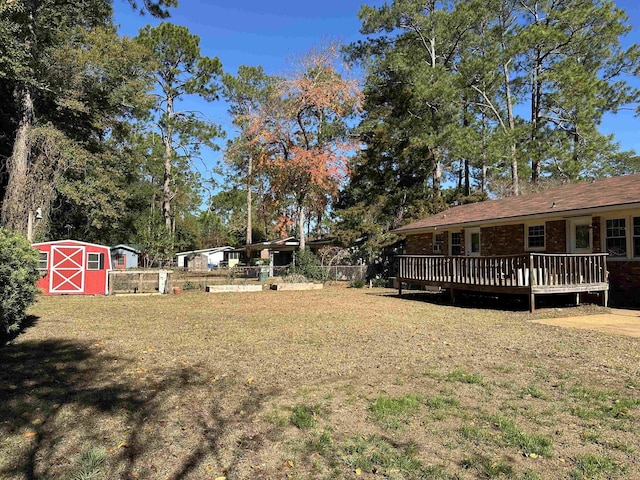 view of yard featuring fence, an outdoor structure, a deck, and a storage unit