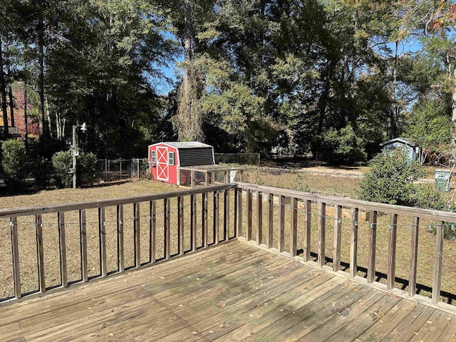 wooden deck featuring a shed, fence, and an outbuilding